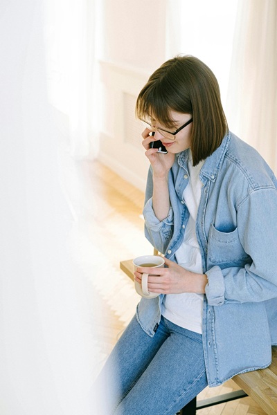 Woman practicing English conversation on phone while holding coffee